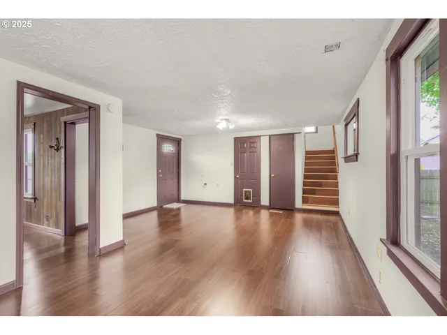 a view of an empty room with wooden floor and windows