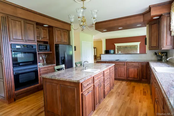 a kitchen with stainless steel appliances granite countertop a kitchen island a stove a sink and a refrigerator