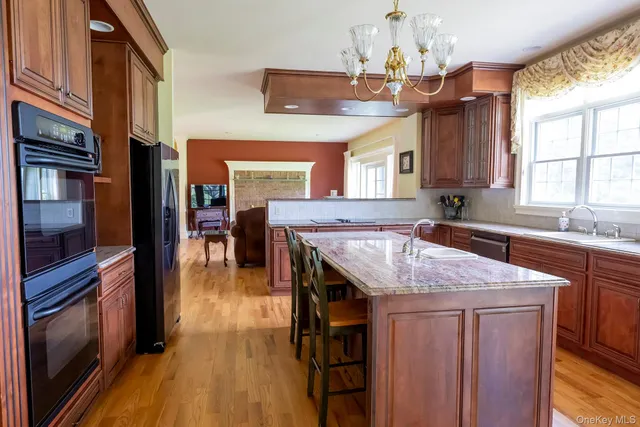 a dining hall with stainless steel appliances granite countertop a kitchen island a stove and a sink