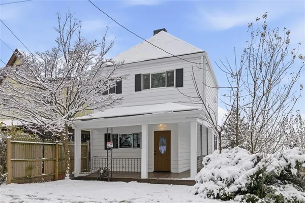a front view of a house with a large tree