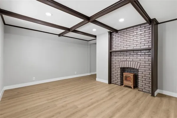 an empty room with wooden floor fireplace and windows