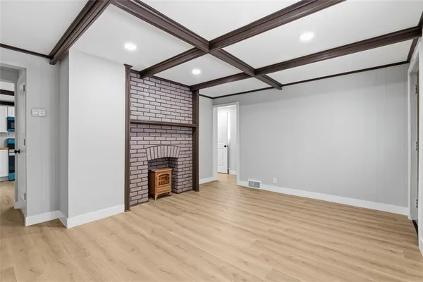 a view of an empty room with wooden floor a ceiling fan and windows