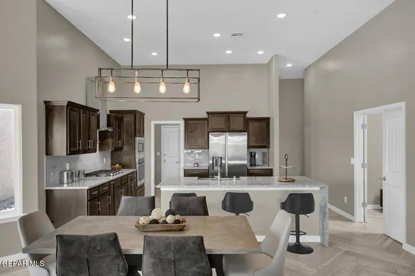 a kitchen with stainless steel appliances granite countertop a stove a refrigerator a kitchen island a couches and chairs