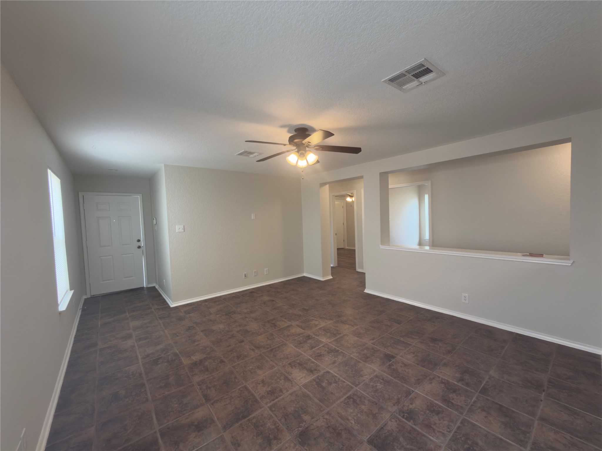 255 Myrtle Street Kyle, TX 78640 - Photo 10 of 31 Spacious living area featuring tile flooring, neutral wall tones, a ceiling fan with integrated lighting, and a decorative wall cut-out