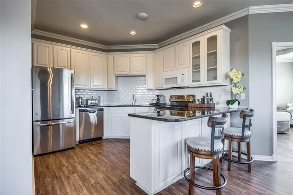 a kitchen with granite countertop a refrigerator stove a sink and dishwasher with wooden floor