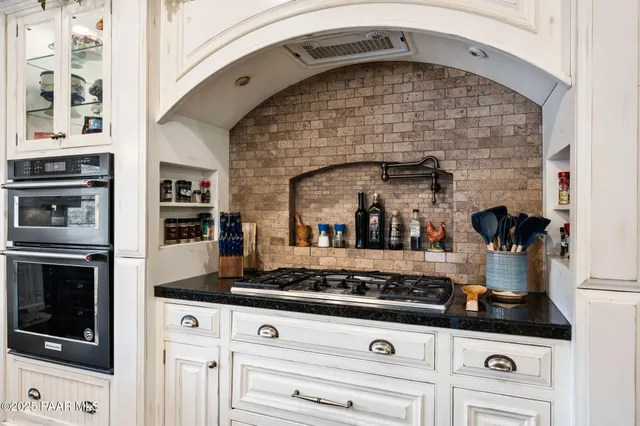 a kitchen with stainless steel appliances kitchen island granite countertop a refrigerator a stove a sink and a large oven with wooden floor