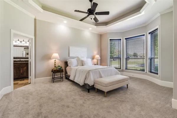 a spacious bedroom with a bed painting on wall and a large window