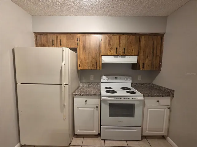 a white refrigerator freezer and a stove sitting inside of a kitchen