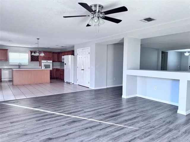 a view of a kitchen with a ceiling fan hardwood floor and a ceiling fan