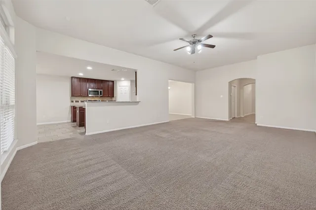 a view of a livingroom with a flat screen tv ceiling fan and window