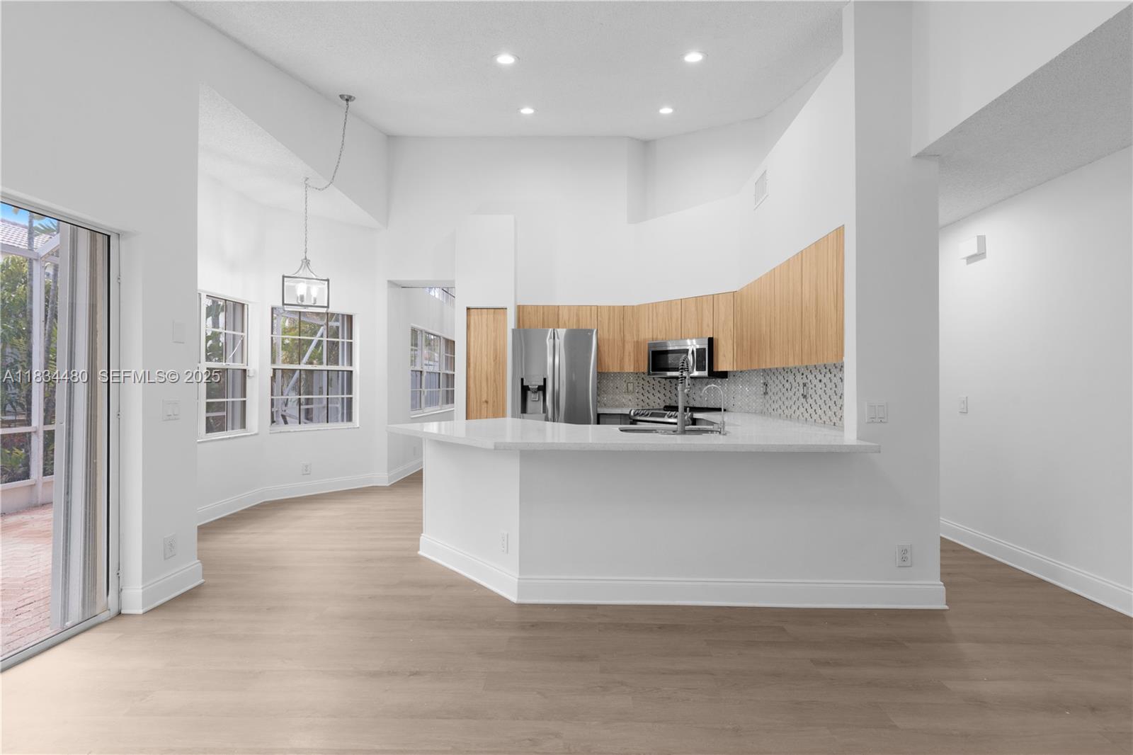 1525 Seabay Road Weston, FL 33326 - Photo 14 of 29 a large white kitchen with kitchen island a stove a refrigerator a sink and a large window