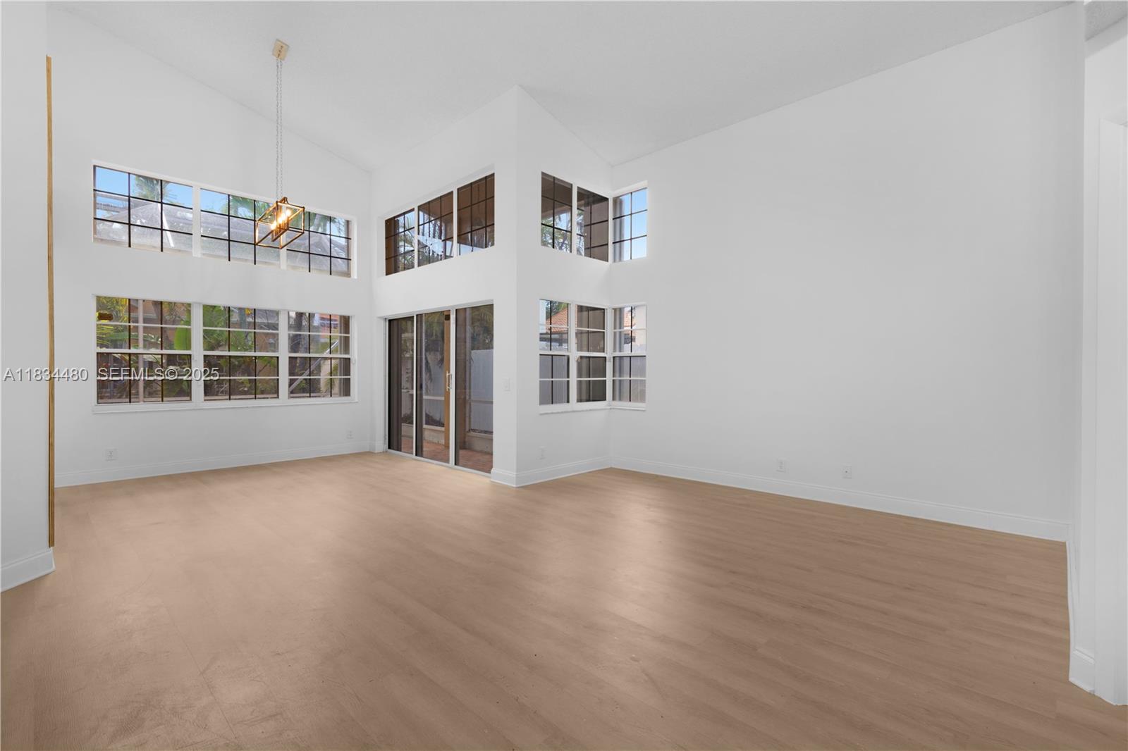 1525 Seabay Road Weston, FL 33326 - Photo 4 of 29 a view of an empty room with a window and wooden floor