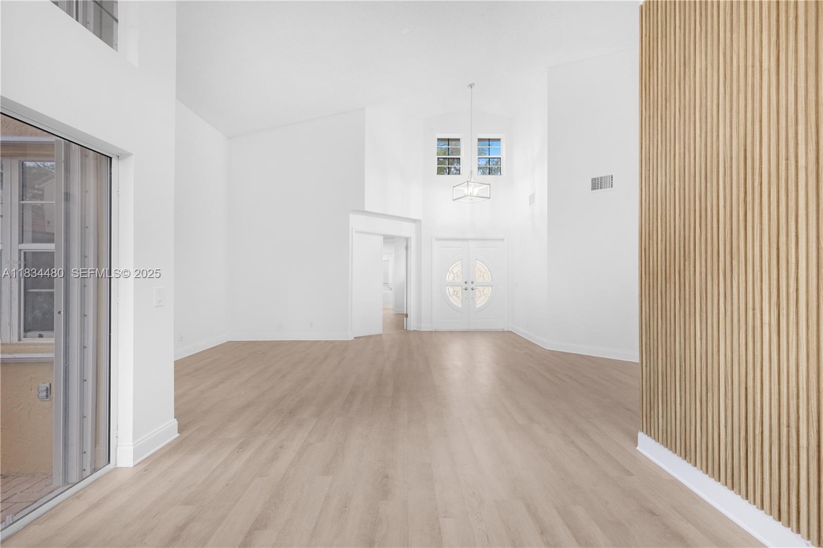 1525 Seabay Road Weston, FL 33326 - Photo 6 of 29 an empty room with wooden floor and windows