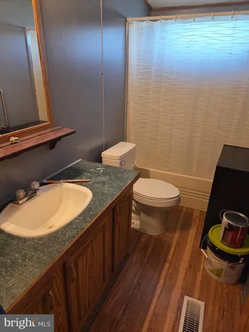 a bathroom with a granite countertop sink a toilet a mirror and shower