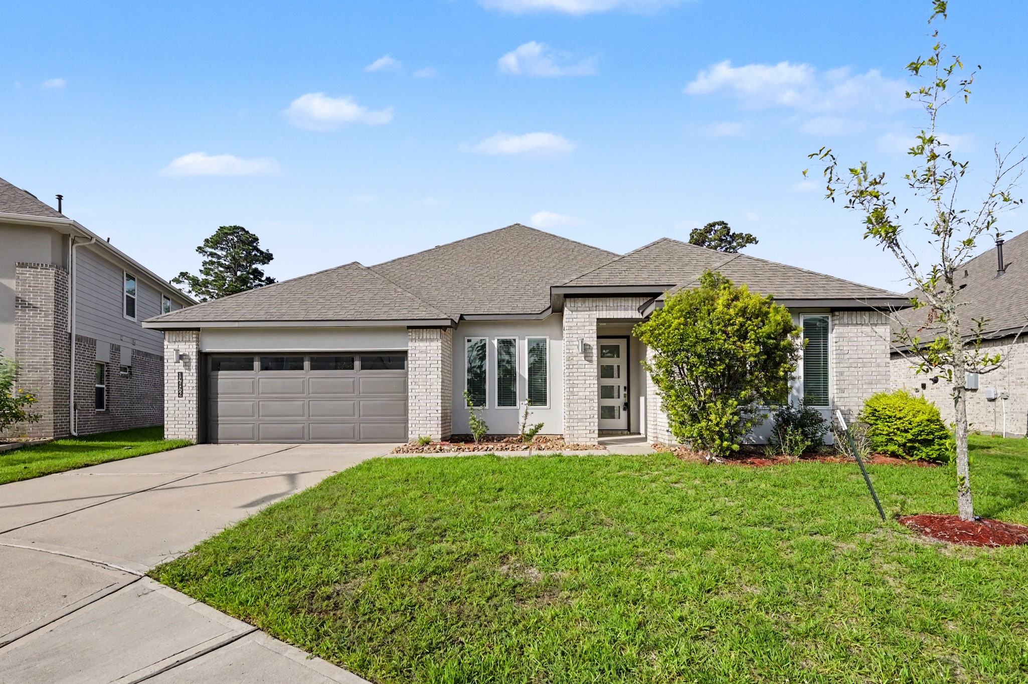 14162 Primrose Ridge Lane Conroe, TX 77384 - Photo 3 of 48 Charming single-story home with a modern brick exterior, two-car garage, and well-maintained landscaping on a spacious lawn.