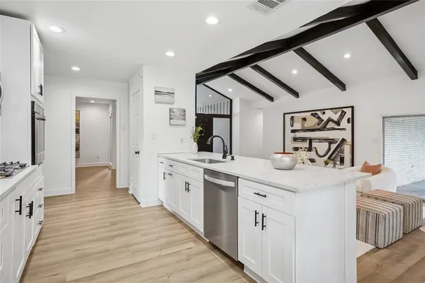 a large white kitchen with a sink and dishwasher with wooden floor