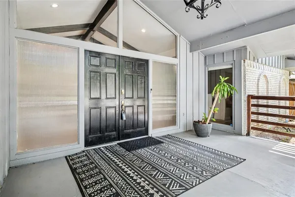 a view of an empty room with wooden floor and a rug