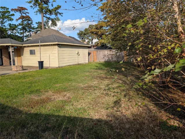 a view of a yard in front of a house with plants and large tree