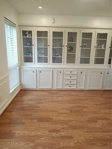 a view of an empty room with wooden floor and cabinets