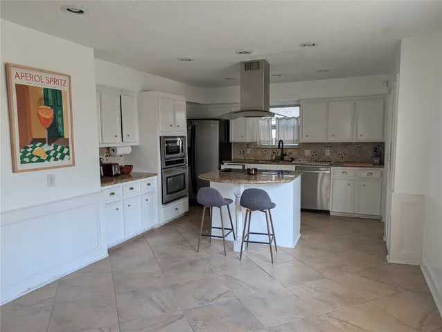 a kitchen with stainless steel appliances a sink a stove a refrigerator cabinets and a window