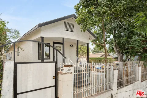 a view of a white house with iron fence