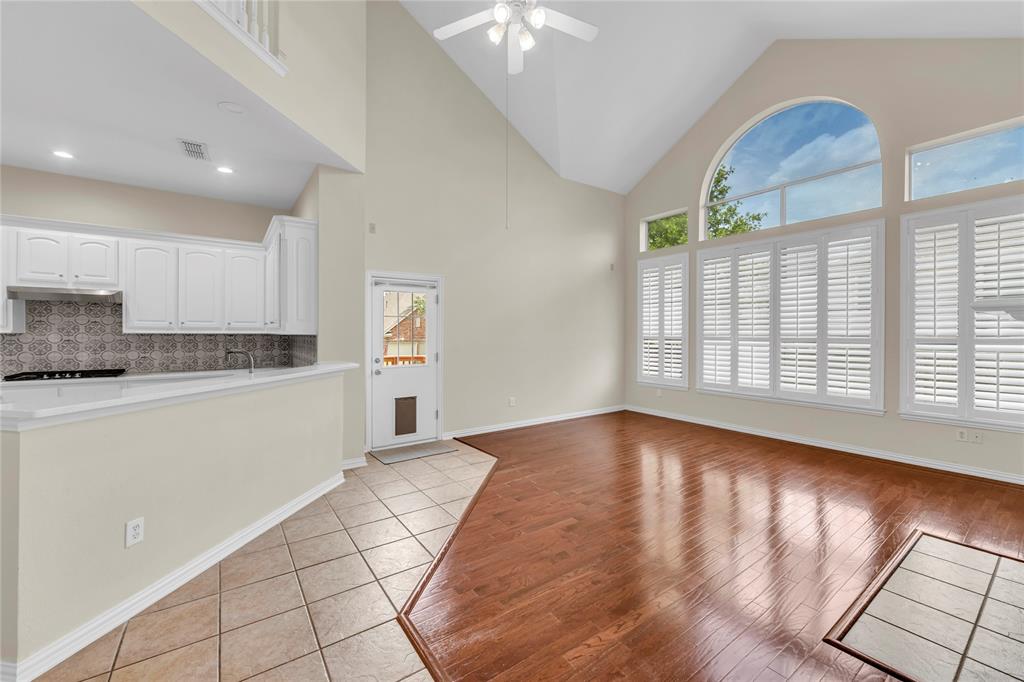 3920 Autumn Lane Bedford, TX 76021 - Photo 18 of 36 Vaulted ceiling living area featuring a large arched window, multiple rectangular windows with white plantation shutters, and wood-finish flooring