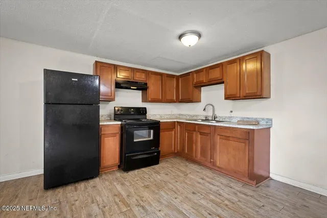 a kitchen with granite countertop a refrigerator stove top oven and sink