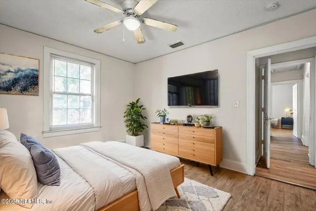 an empty room with wooden floor fan and windows