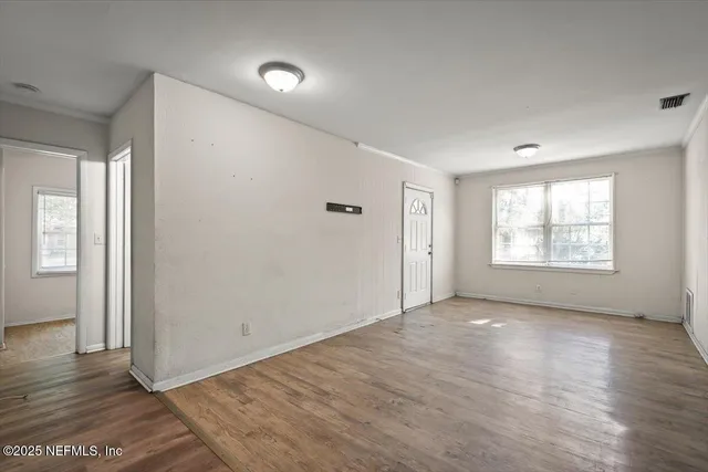 an empty room with wooden floor and windows