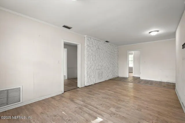 a view of an empty room with wooden floor and closet