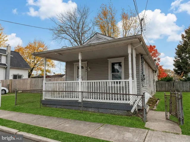 a view of a house with a small yard and a large tree and wooden fence