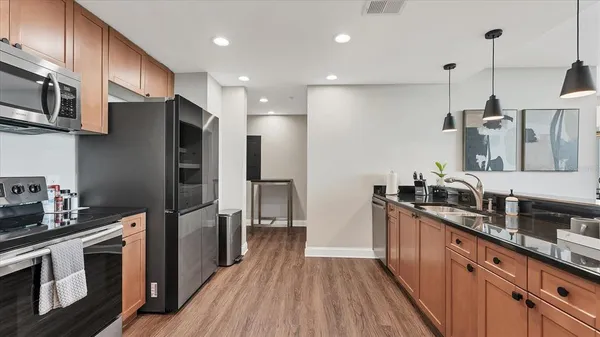 a kitchen with stainless steel appliances granite countertop a refrigerator a stove a sink dishwasher and a oven with wooden floor