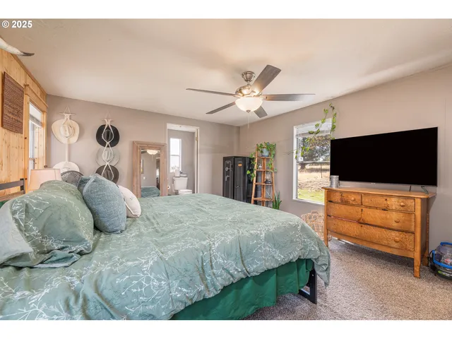 a spacious bedroom with a bed and a flat screen tv