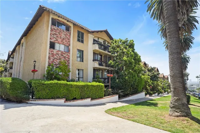 a front view of a multi story residential apartment building with yard and green space