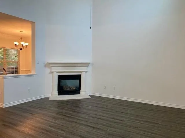 a view of an empty room with wooden floor and a fireplace