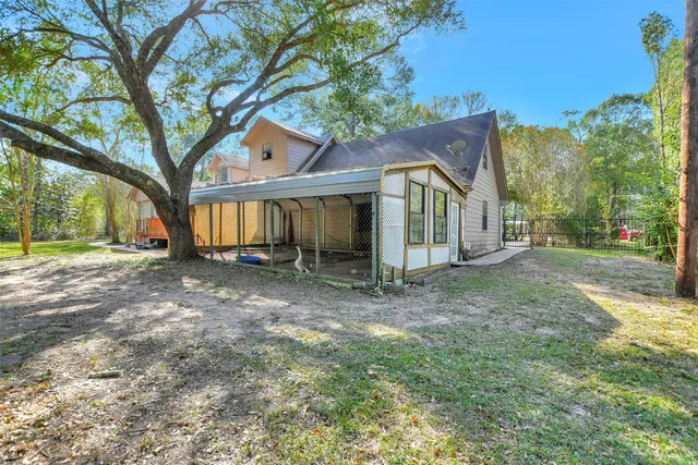 a view of a house with a yard and large tree