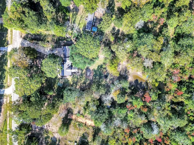 an aerial view of residential house with outdoor space and trees all around