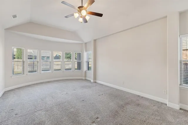 an empty room with windows and fan