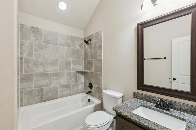 a bathroom with a granite countertop sink toilet mirror and bathtub