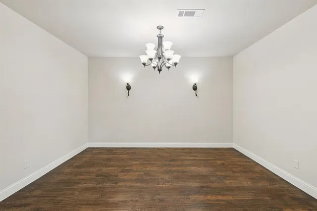 an empty room with wooden floor chandelier fan and windows