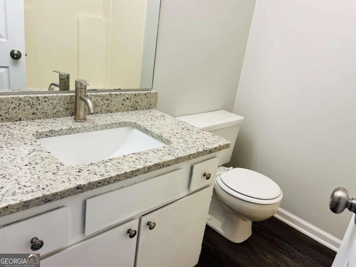 5614 Windwood Road, Unit 5614 Atlanta, GA 30349 - Photo 18 of 26 a bathroom with a granite countertop toilet sink and mirror