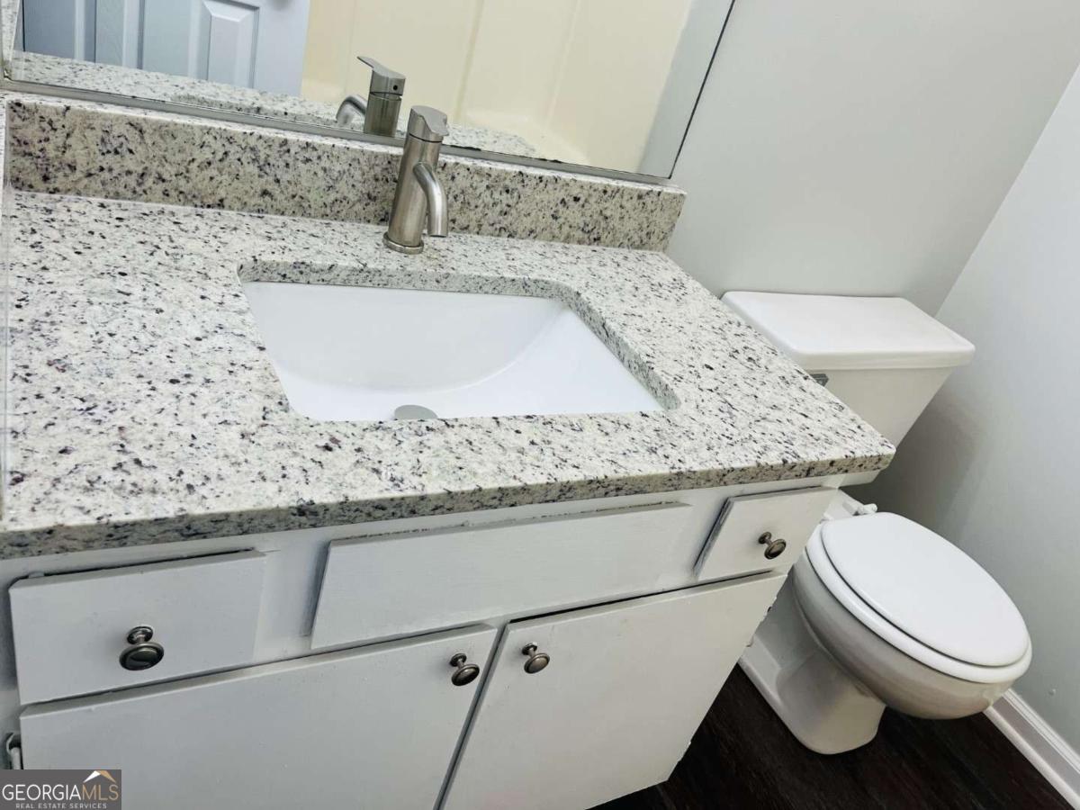 5614 Windwood Road, Unit 5614 Atlanta, GA 30349 - Photo 19 of 26 a bathroom with a granite countertop toilet sink and mirror