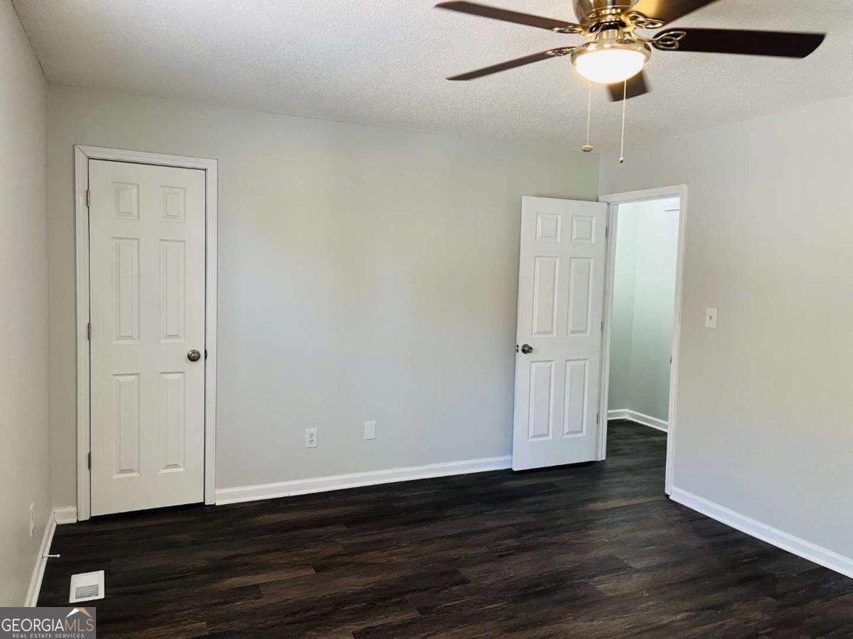 5614 Windwood Road, Unit 5614 Atlanta, GA 30349 - Photo 23 of 26 an empty room with wooden floor closet fan and windows