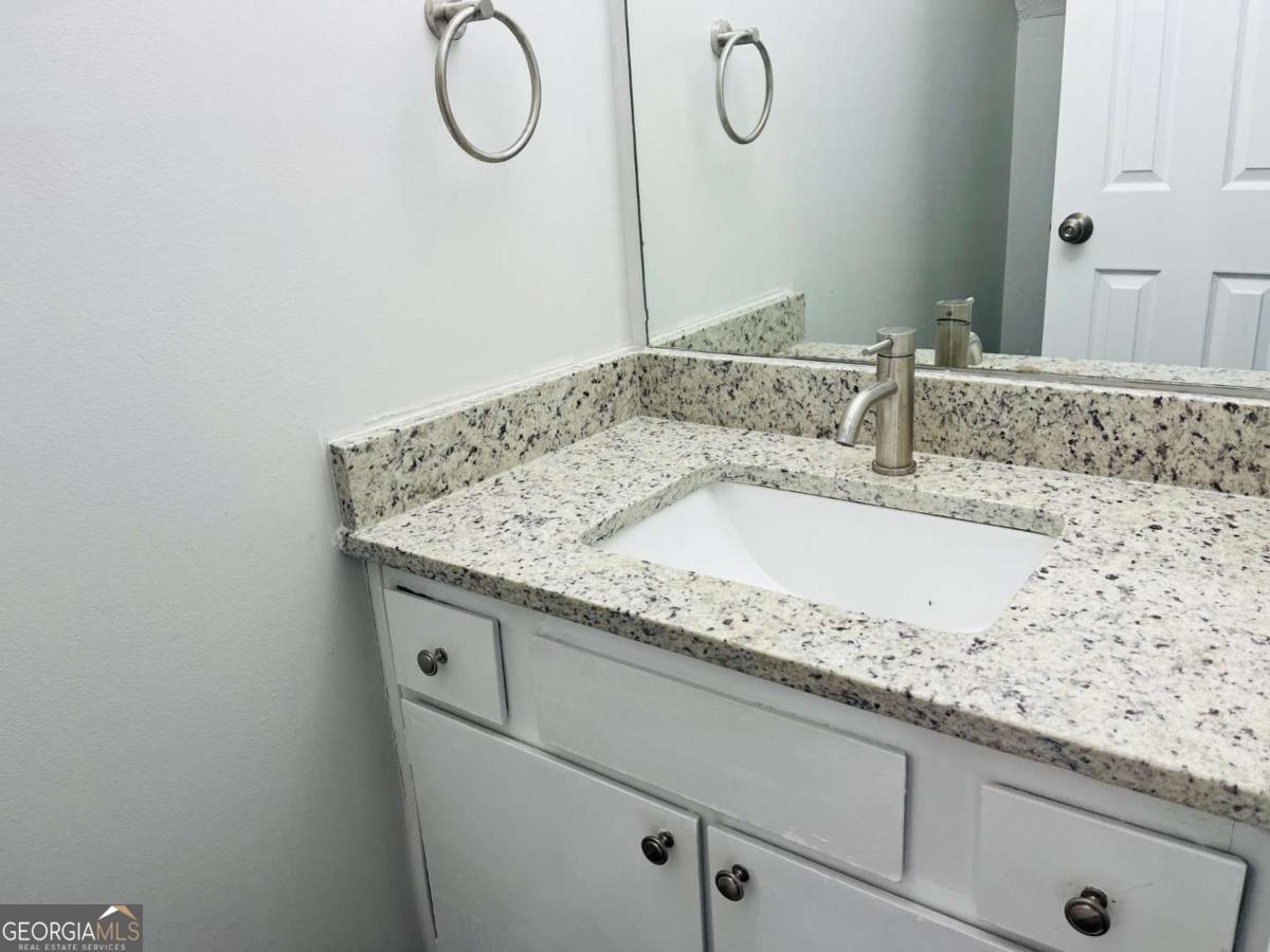 5614 Windwood Road, Unit 5614 Atlanta, GA 30349 - Photo 5 of 26 a bathroom with a granite countertop sink and a mirror