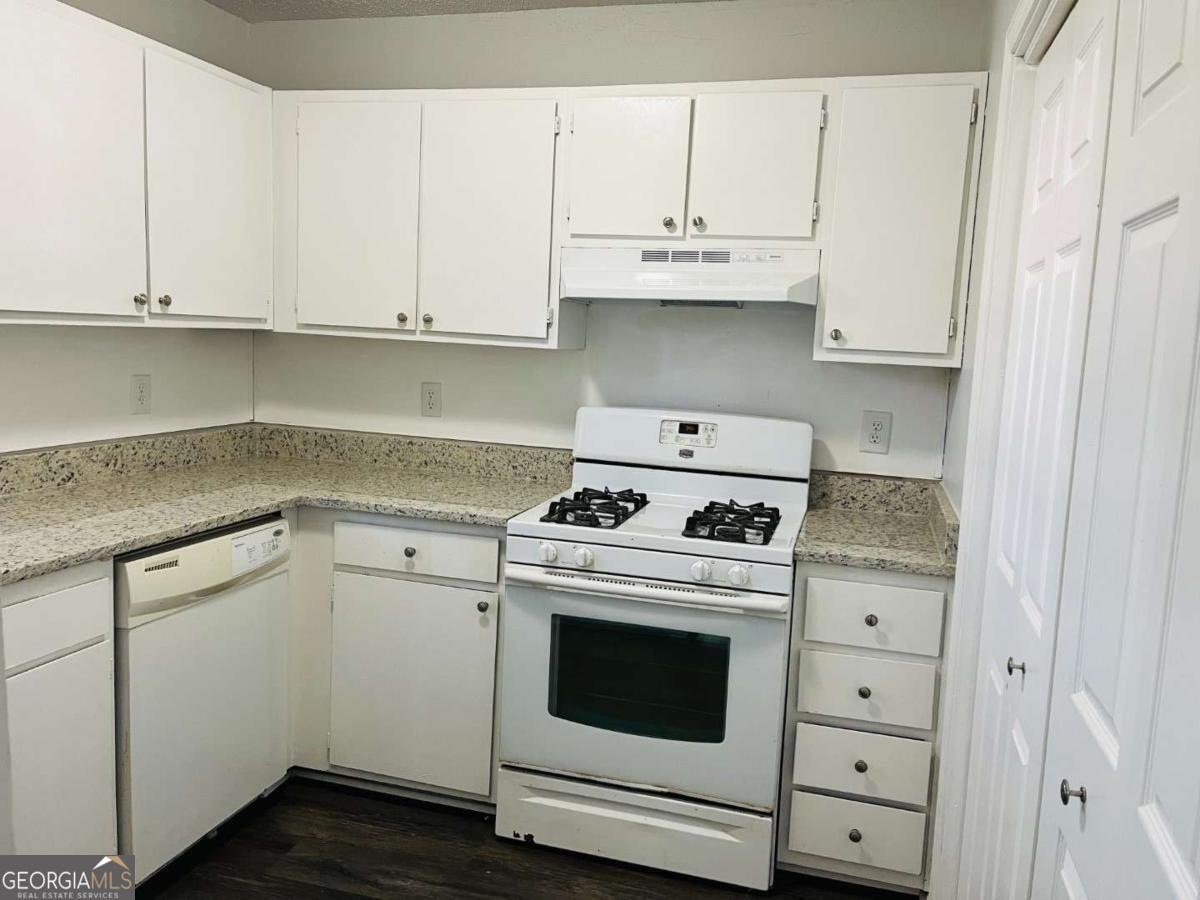 5614 Windwood Road, Unit 5614 Atlanta, GA 30349 - Photo 6 of 26 a kitchen with granite countertop white cabinets and white appliances