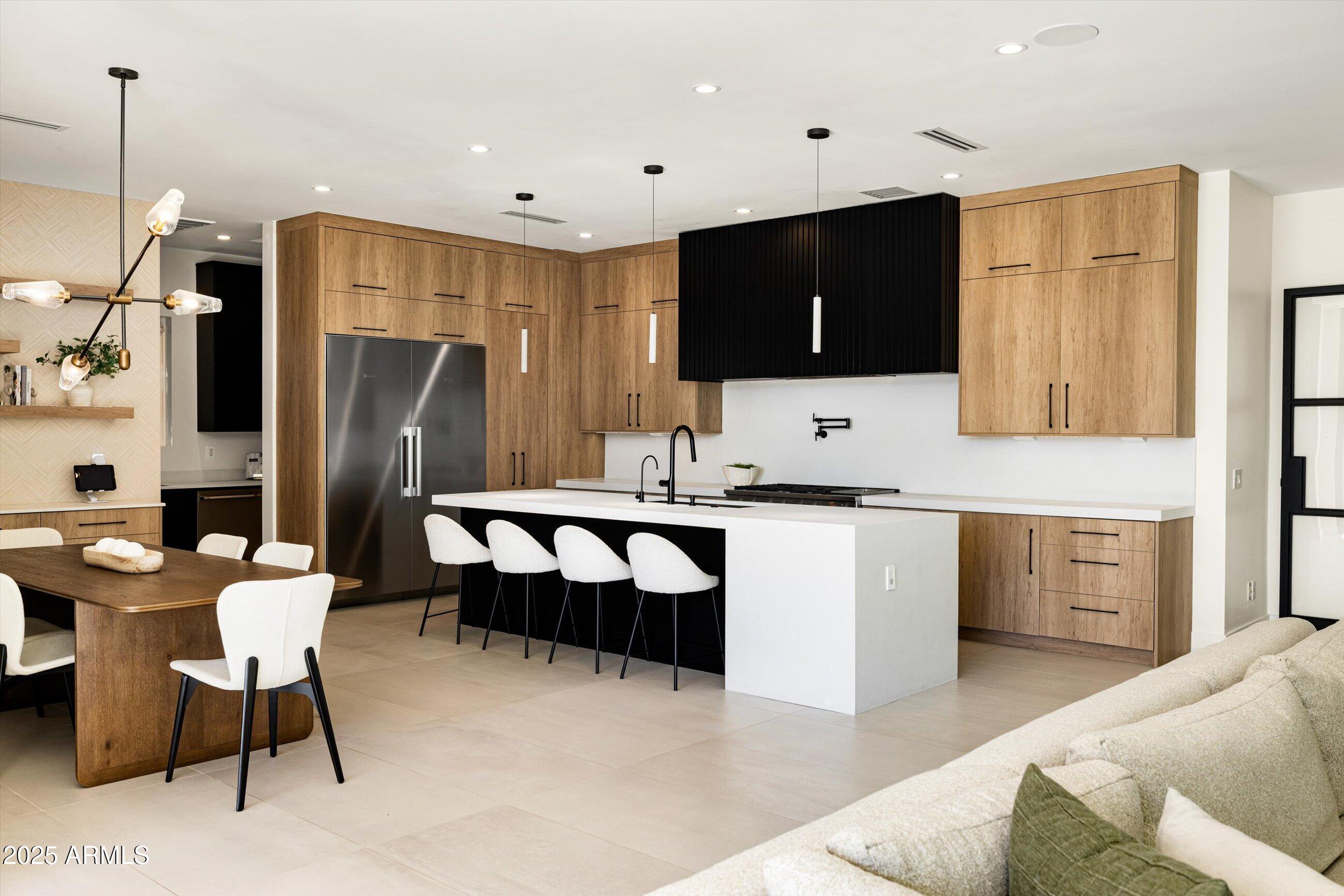 a large kitchen with stainless steel appliances kitchen island granite countertop a refrigerator and a stove top oven