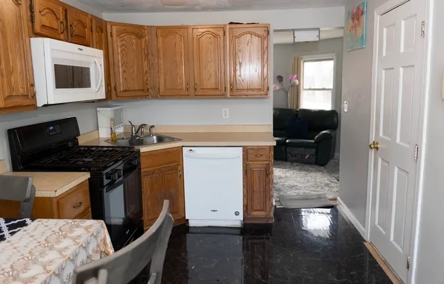 a kitchen with stainless steel appliances a stove a sink cabinets and a wooden floor