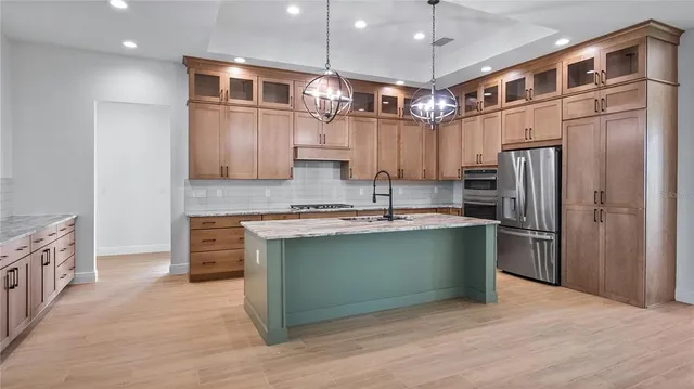 a kitchen with stainless steel appliances granite countertop a refrigerator a stove and a sink