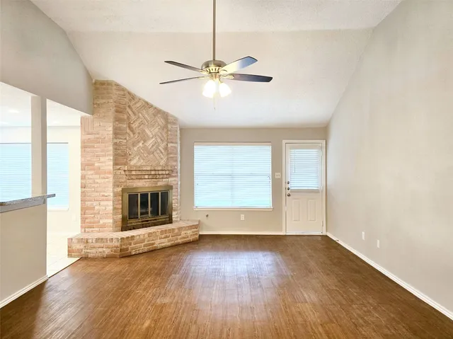 an empty room with wooden floor fan and windows