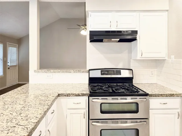 a kitchen with granite countertop a stove and a white cabinets